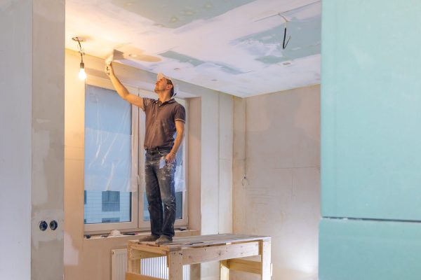 Worker make repairs in new apartment. Man plaster walls and ceilings